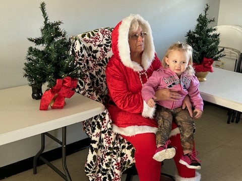 Mrs. Clause with a young girl on her lap. 