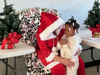 A young girl sitting on Mrs. Clause's lap. 