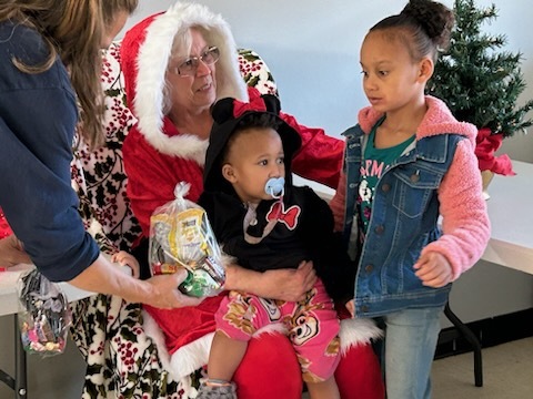 Two young girls sitting on Mrs. Clause's lap. 