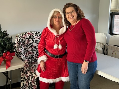 A woman standing with Mrs. Clause.