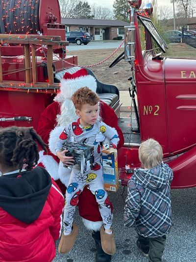 A young man with Mrs. Clasue near a fire truck. 