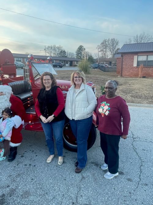 Three women standing near a fire truck. 