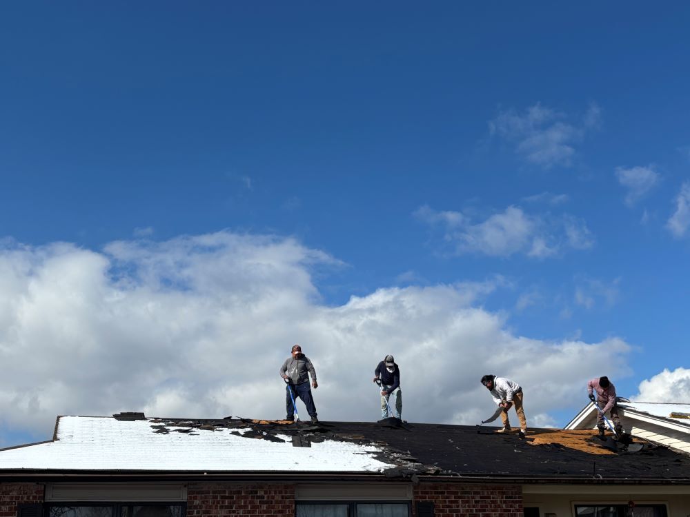 Men working on a roof removing shingles. 
