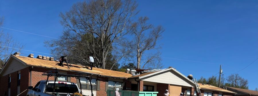 Roof with two men standing on it, partially conpleted. 
