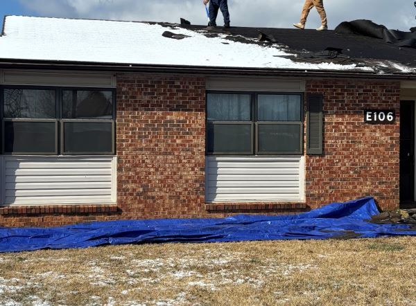 Workers applying roofing paper on a roof. 